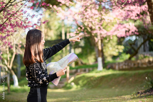 Beautiful woman holding a map in a park full of cherry blossoms