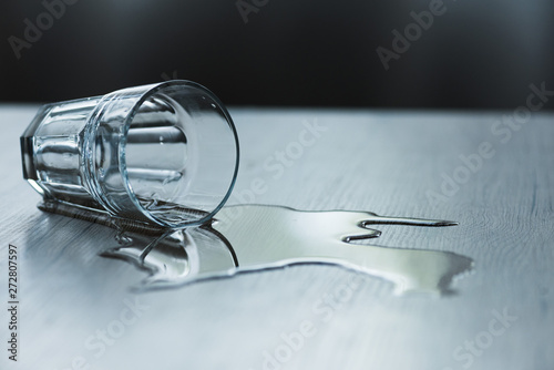 glass with spilled water on textured wooden surface photo