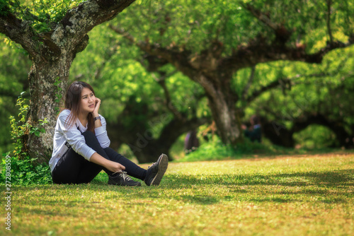 Asian girl sitting under a tree in the park