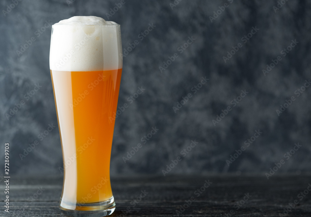 A glass of wheat unfiltered beer on a dark background with copyspace