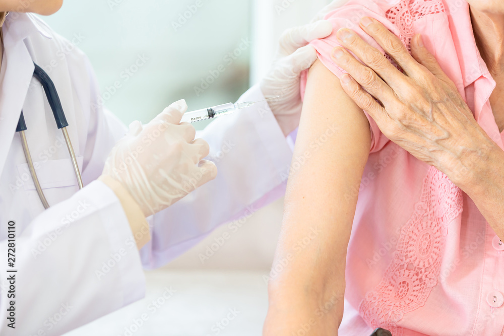 Close up,asian female doctor with syringe doing injection vaccine,flu,influenza in the shoulder of senior woman, nurse injecting,vaccinating elderly patient,vaccination,medicine,health care concept Close up,asian female doctor with syringe doing injection vaccine,flu,influenza in the shoulder of senior woman, nurse injecting,vaccinating elderly patient,vaccination,medicine,health care concept