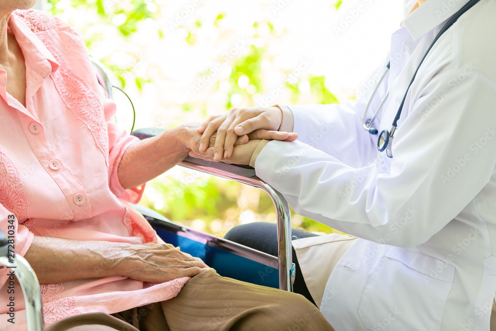 Closeup of hand medical female doctor or nurse holding senior patient hands and comforting her,.Caring caregiver woman supporting disabled elderly people on wheelchair,help,love,health care concept - obrazy, fototapety, plakaty 
