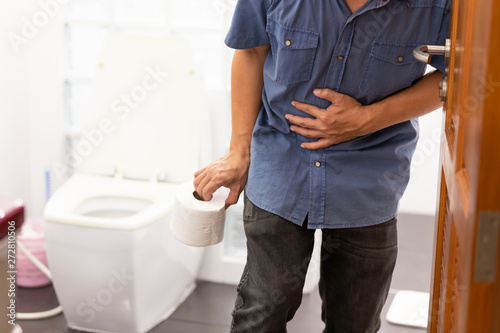 Asian man suffers from diarrhea holding tissue roll  near a toilet bowl,man have abdominal pain,stomachache,constipation in bathroom,sick people hand from the belly diarrhea,stomach health problem photo