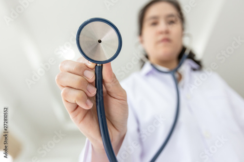 Asian female medical doctor holding stethoscope, young nurse checking patient using stethoscope,standing while looking at camera in hospital,health care concept