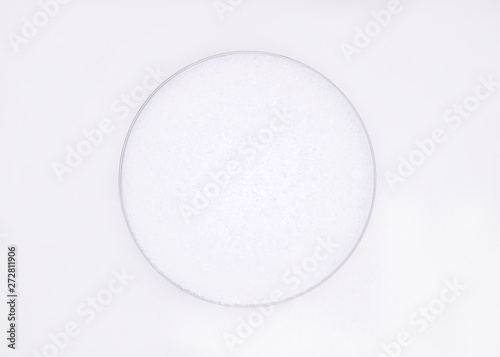 White sea salt crystals in round cap on a white background