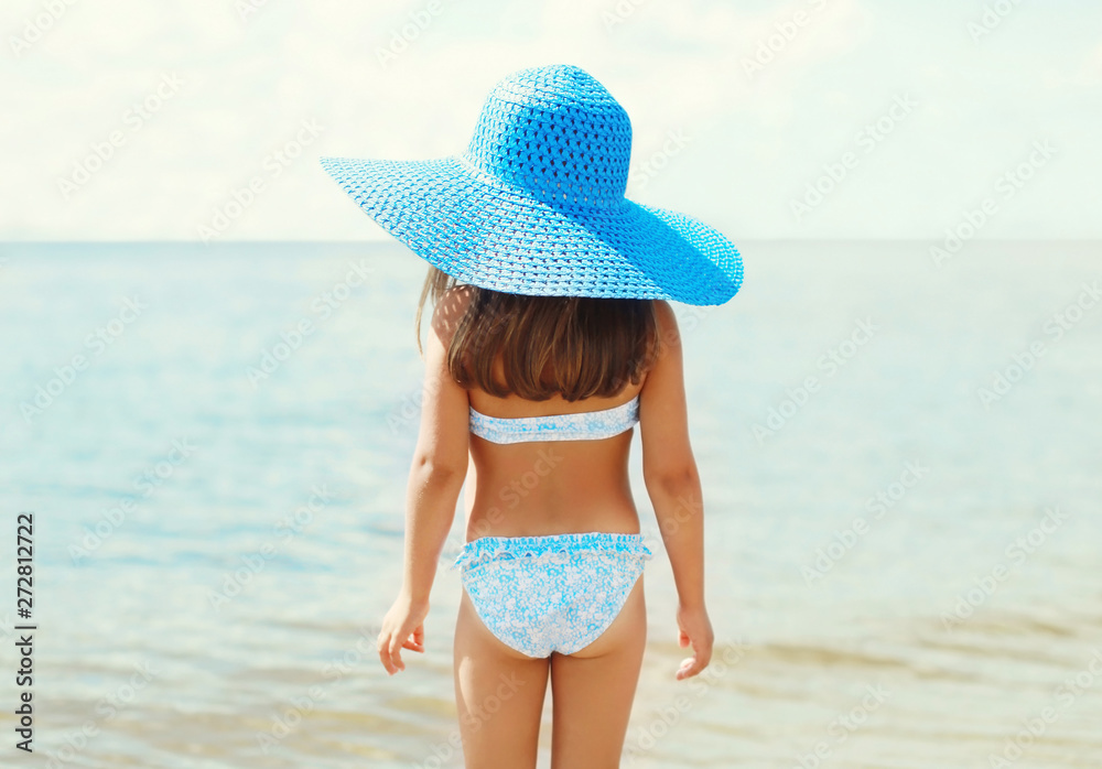 Summer holidays, vacation concept - little girl in straw hat on beach over sea background