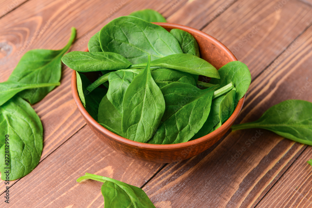 Bowl with fresh spinach on wooden background Bowl with fresh spinach on wooden background