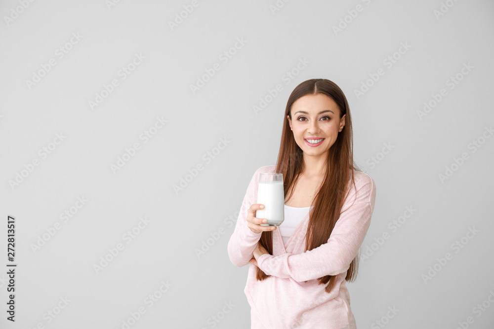 Beautiful woman with glass of tasty milk on light background Beautiful woman with glass of tasty milk on light background