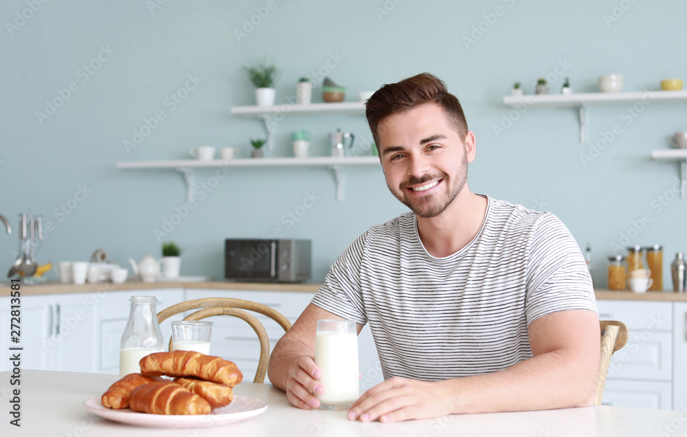 Handsome man drinking tasty milk in kitchen at home Handsome man drinking tasty milk in kitchen at home