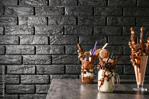 Delicious freak shakes on table against dark brick background photo