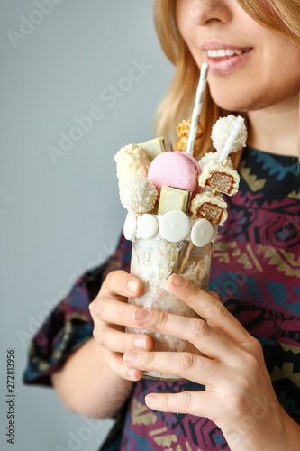 Woman with delicious freak shake on grey background
