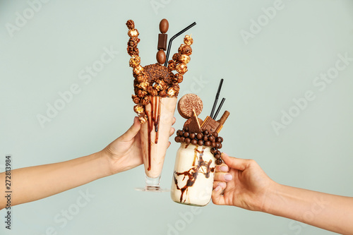 Female hands with delicious freak shakes on grey background photo