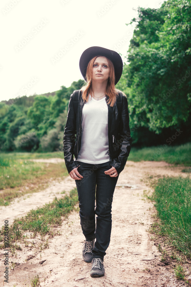 Young female tourist with a pink backpack and leather cowboy style hat looking at the distance. portrait. adventure concept, vertical photo. active lifestyle, countryside hiking Young female tourist with a pink backpack and leather cowboy style hat looking at the distance. portrait. adventure concept, vertical photo. active lifestyle, countryside hiking