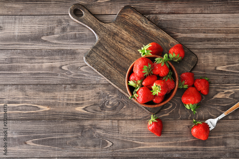 Bowl with red strawberry on wooden table