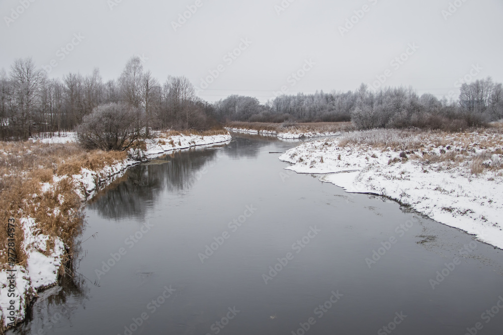 Winter landscape on the river. Snow picture. Snow and river. Cloudy snow day.