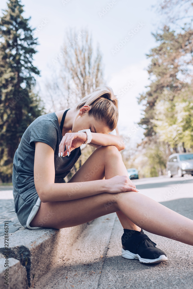 injured sportswoman crying while sitting on pavement near roadway