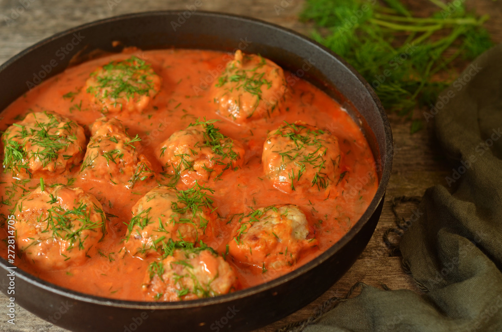 Turkey meatballs in tomato sauce in a pan on a wooden background
