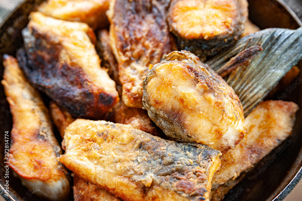 Close-up of fried fish in a frying pan.