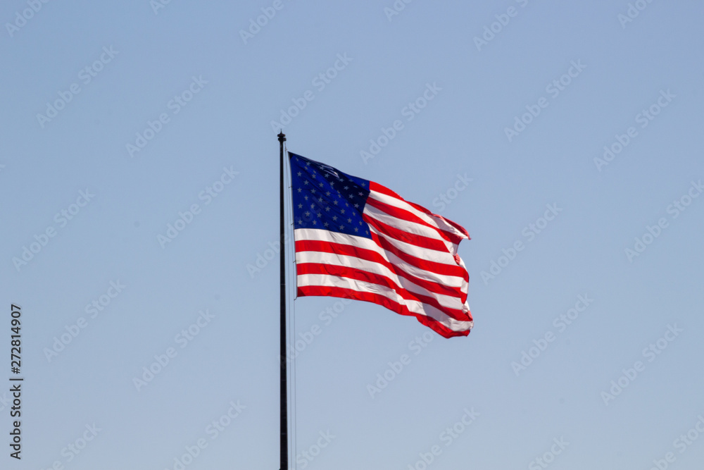 USA American flag waving in the wind on clear blue sky in background