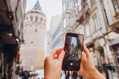 Popular tourist destination in Istanbul, Turkey. A woman makes a photo from the phone camera in Istanbul. Man in Istanbul taking pictures with a smartphone in front of the Galata Tower