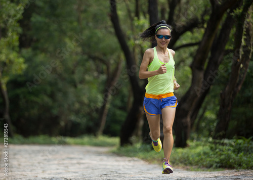 Young fitness woman trail runner running in forest