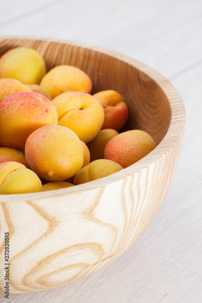ripe organic apricots fruits in ash tree wooden bowl on a white wooden background ripe organic apricots fruits in ash tree wooden bowl on a white wooden background