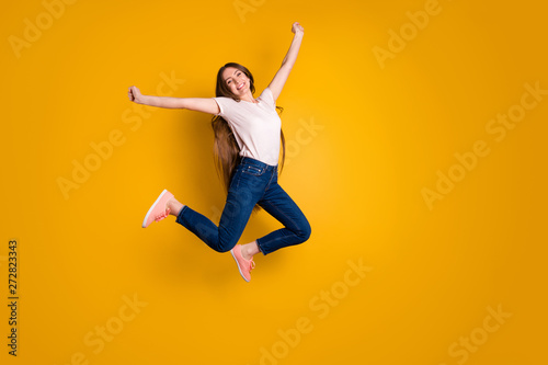 Full length side profile body size photo beautiful amazing she her stylish lady very long hair flight jump high spread hands arms wear casual jeans denim pink shoes t-shirt isolated yellow background