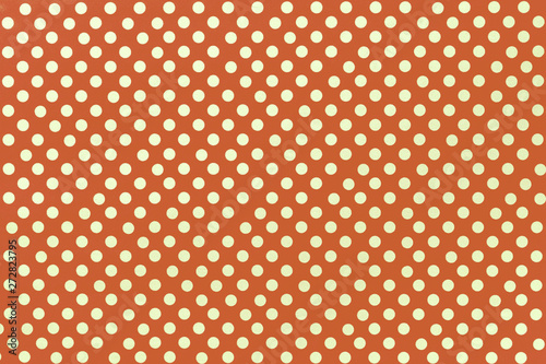 Light orange background from wrapping paper with a pattern of golden polka dot closeup.