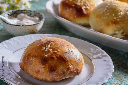 Homemade samsa as a buns stuffed with beef or lamb and vegetables from a simple bread dough next to sauce are on a table and ready for eatting, close up