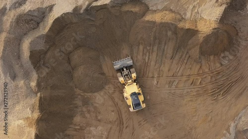 Overhead aerial view loading bulldozer in open air quarry.