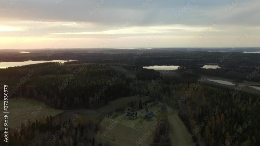 Sunset aerial drone shot of forest and fields. Flying over Finland landscape.
