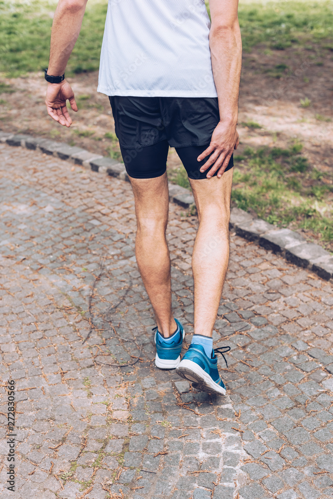 cropped shot of sportsman standing on pavement and touching injured leg cropped shot of sportsman standing on pavement and touching injured leg