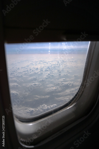 Airplane window overlooking the beautiful clouds and the earth. Sunset in flight on vacation. Tourist theme. Stock photo