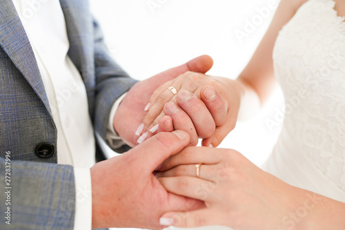 Closeup of a bride and groom holding hands isolated over a white background.