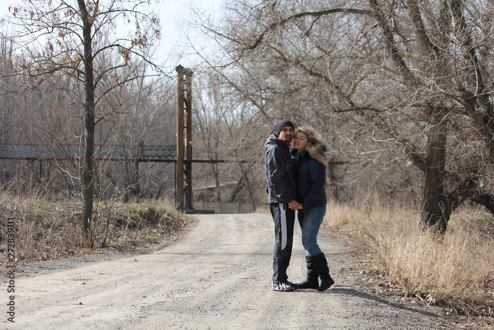 Young lovely couple standing on the road leading to the old bridge Young lovely couple standing on the road leading to the old bridge