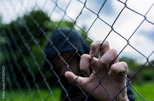 Принти на полотні Young unidentifiable teenage boy holding the wired garden at the correctional institute, conceptual image of juvenile delinquency, focus on the boys hand