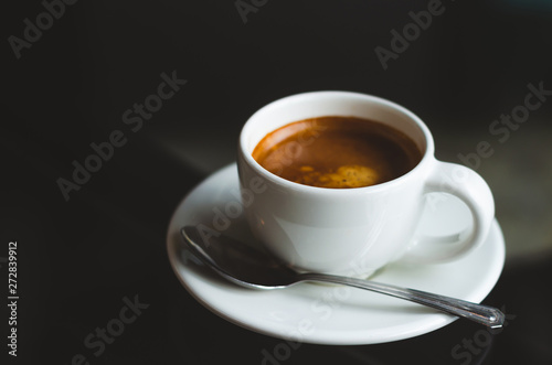 close up modern hot black coffee the espresso on dark background with coffee bubble foam pattern and texture in white cup looking and feel so delicious on wood table in coffee shop.