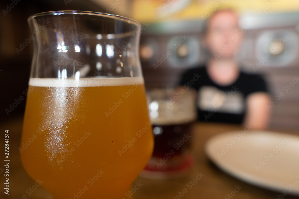Mug of cold beer with misted glass. Girl in blur on background. Mug of cold beer with misted glass. Girl in blur on background.