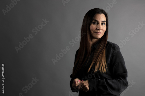 Portrait of middle-aged woman, half body with gray executive background.