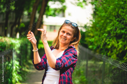 Smiling young woman wearing a plaid shirt clapping her hands with excitement – Casually dressed millennial cheerfully applauding on the street