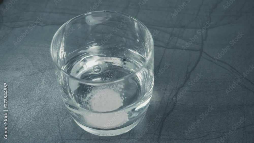 effervescent calcium tablet dissolve slow motion in a glass with water in the kitchen. effervescent calcium tablet dissolve slow motion in a glass with water in the kitchen.