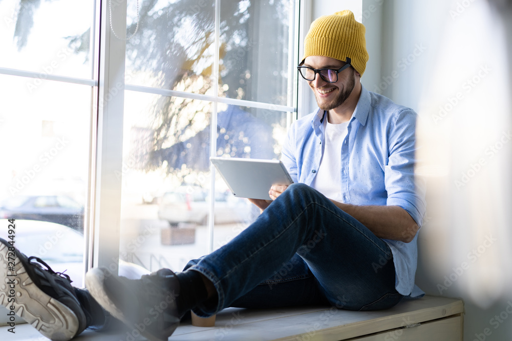 Man using Tablet for Work and Browsing Information, Young creative manager sitting by the window.