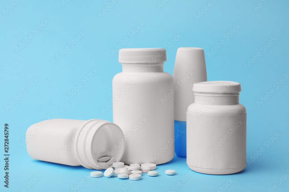 Containers and scattered pills on color background Containers and scattered pills on color background