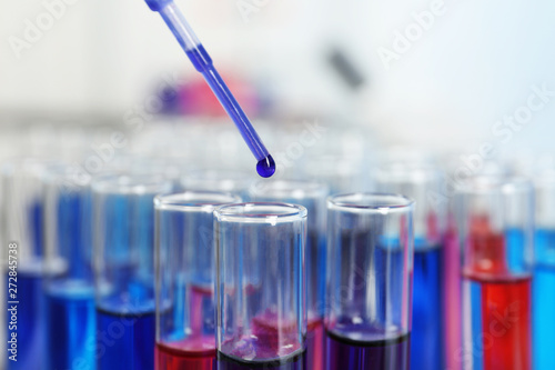 Dripping reagent into test tube with sample in chemistry laboratory, closeup