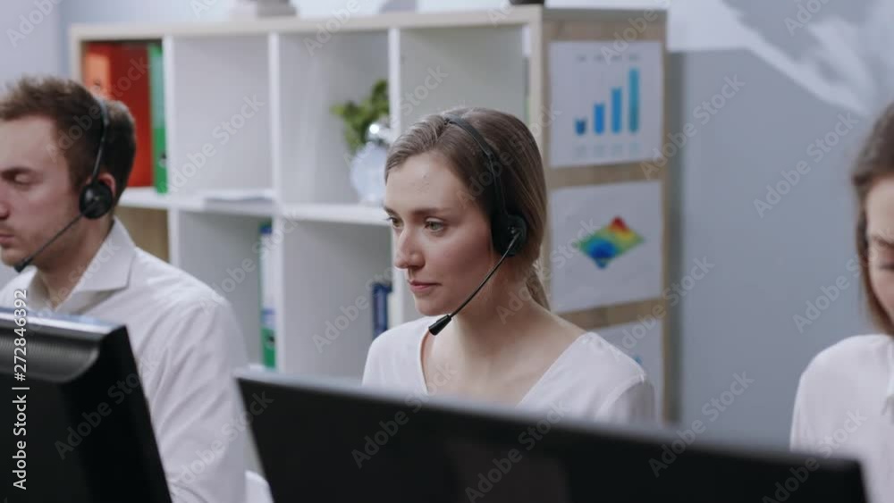Portrait young woman work operator taking look at camera smile calls in busy call center office business worker computer corporate headset job man service group finance phone slow motion