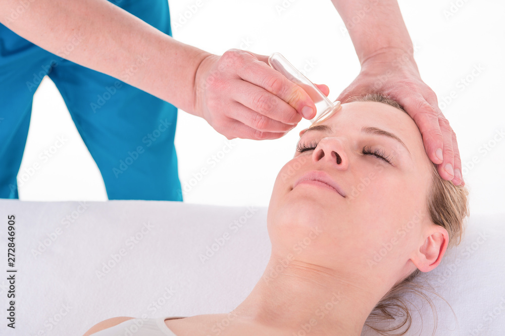 Fototapeta premium Young Woman receives facial cupping massage facial rejuvenation treatment at acupuncture wellness spa