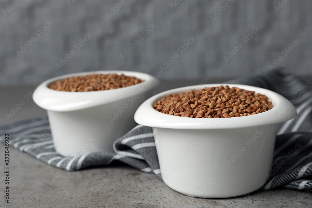 Uncooked buckwheat in bowls on table. Space for text Uncooked buckwheat in bowls on table. Space for text