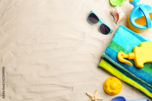 Flat lay composition with colorful beach toys on sand. Space for text