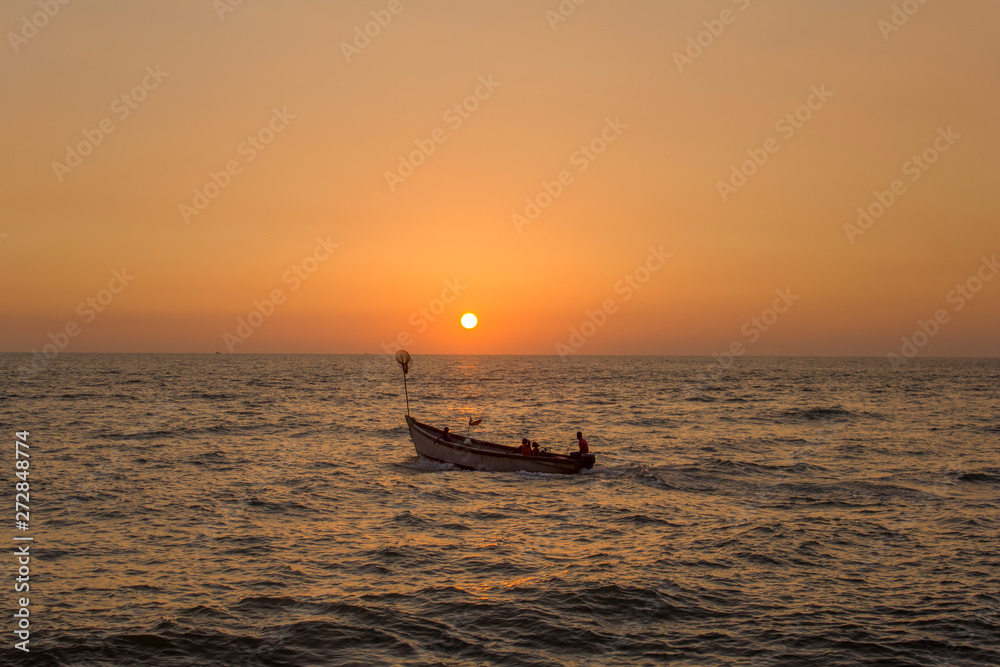 young family with children in a large pleasure boat with a motor in the ocean against the bright orange yellow sky of sunset and sun