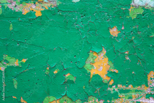 old dirty shabby green wall with cracks  scratches and peeling yellow paint. rough surface texture